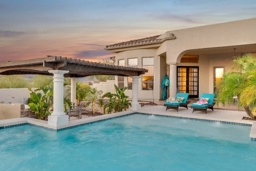 home value step 02 pool pergola Pool and pergola behind a stucco home at dusk